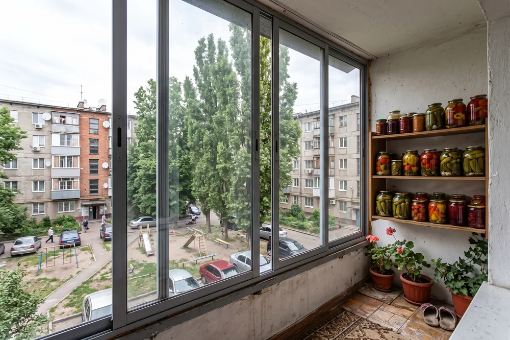 Холодный застеклённый балкон, на полках вдоль стены банки с заготовками