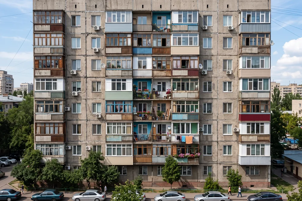 Фасад многоэтажки, где балконы застеклены вразнобой: разные рамы, разные цвета